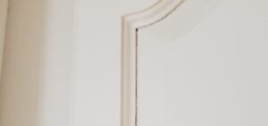 Painted cabinet door with visible cracks and peeling due to wood expansion and contraction