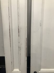 Close-up of chipped and worn painted kitchen cabinet door showing early signs of wear and tear