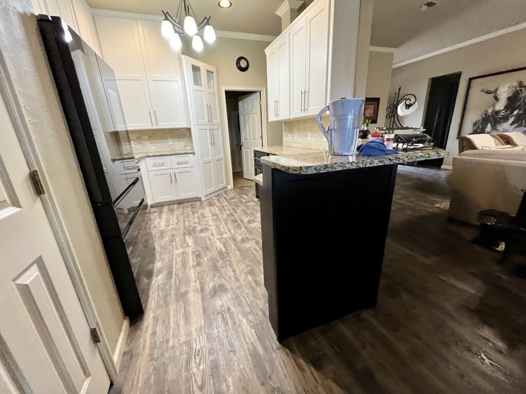  Refreshed two-tone kitchen with white Shaker perimeter cabinets and a dark island with new door and drawer fronts