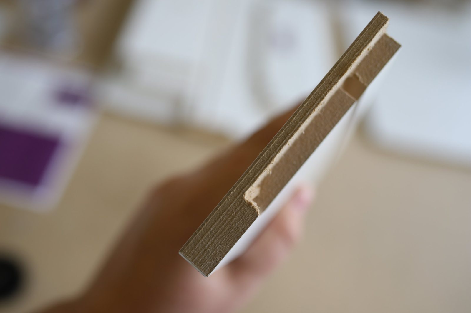 Thermofoil cabinet door edge showing the solid engineered wood fiber core wrapped in a seamless white thermofoil finish